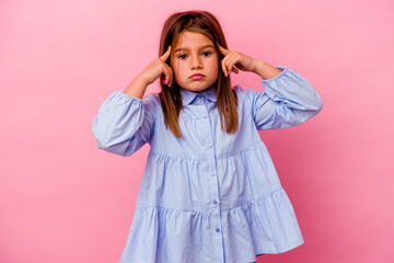 Little caucasian girl isolated on pink background  focused on a task, keeping forefingers pointing...