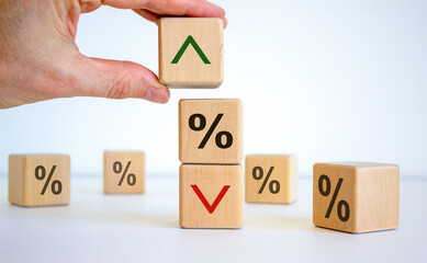 Interest rates symbol. Wooden cubes, businessman changed the direction of an arrow symbolizing that the interest rates are going down or up. Beautiful white background. Business concept. Copy space.