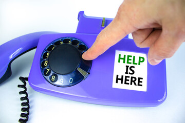 Help is here symbol. Old blue rotary dial telephone. Words 'Help is here'. Beautiful white background. Businessman hand. Business and help is here support concept, copy space. Businessman hand.