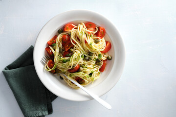 Pasta, spaghetti with tomato in white bowl on grey stone background. Top view.