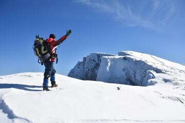 Fototapeta na wymiar Man on top of snowy mountain. Lonely mountaineer get rest on snowy mountain high above the clouds