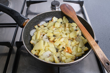 Potatoes cut with onion inside a frying pan