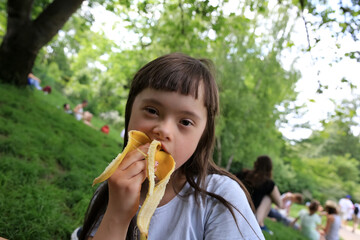 Young girl eating banana in the park