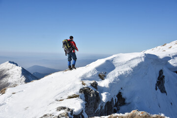 Man on top of snowy mountain. Lonely mountaineer get rest on snowy mountain high above the clouds