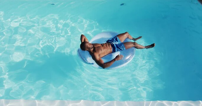 Mixed race man having fun sunbathing on inflatable in swimming pool
