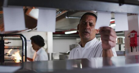 Caucasian male chef taking orders and talking in restaurant kitchen - Powered by Adobe