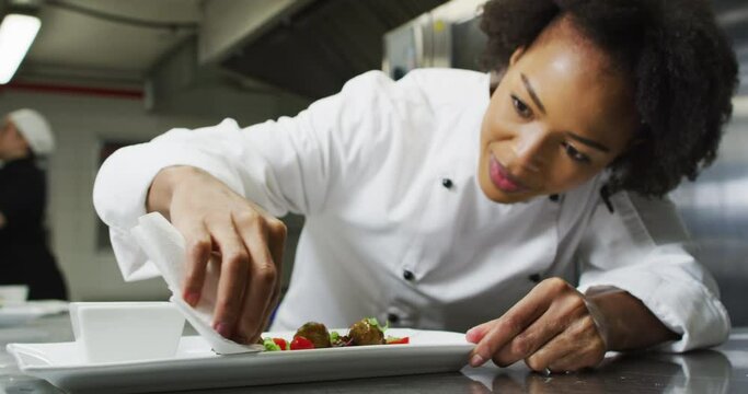 Portrait Of African American Female Chef Garnishing Dish Looking At Camera And Similing