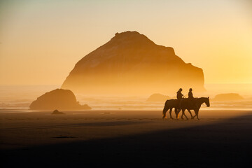 Face Rock, with horses and riders,  at sunset on the southern Oregon coast at Bandon - obrazy, fototapety, plakaty