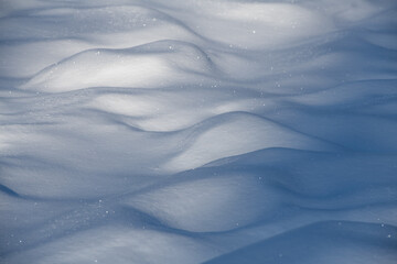 close up snowscape landscape of snow mounds small hills of snow with sunlight and shadow creating abstract design of white smooth fresh snow mounds horizontal format room for type 
