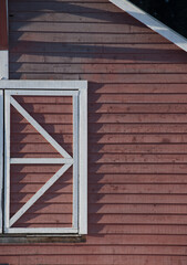 white traditional window frame on red wooden shingled barn framed with geometric shapes of...