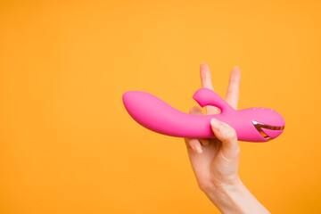Pink sex toy in hand, adult gift, Valentine's Day, 8 March concept. Massager for the clitoris. Useful for a sex shop