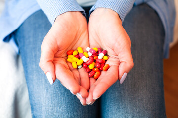 Woman holds many multicolored pills in hands. Taking vitamins, supplements, antibiotic, antidepressant and painkiller medication. Close-up.