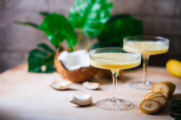 Obraz na płótnie Canvas banana cocktail with coconut milk in a glass on light beige background with palm leaves
