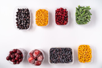 Frozen berries and vegetables in plastic boxes isolated on white background.
