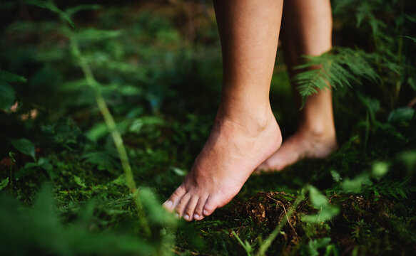 Bare feet of woman standing barefoot outdoors in nature, grounding concept.