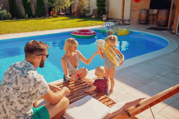 Parents playing with children by the swimming pool