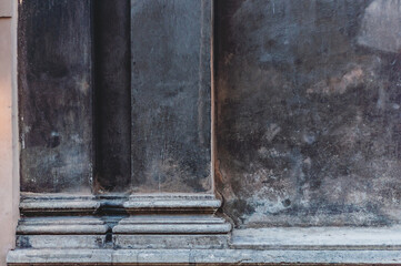 Antique building facade with columns, old dirty plaster, wall darkened with age, rough textured surface, textured background