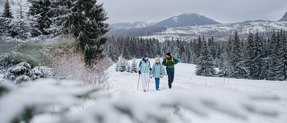 Family with small daughter on a walk outdoors in winter nature, Tatra mountains Slovakia.
