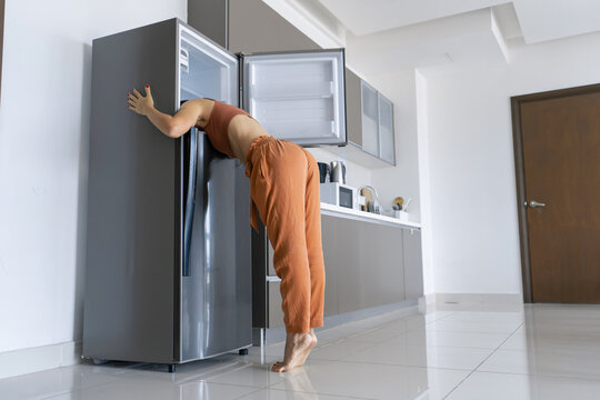 On a hot day, the girl cools with his head in the refrigerator. Broken air conditioner