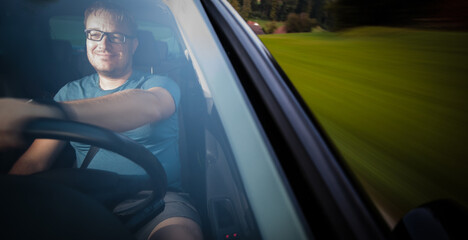 Handsome young driver driving hic car fast yet safely on the road