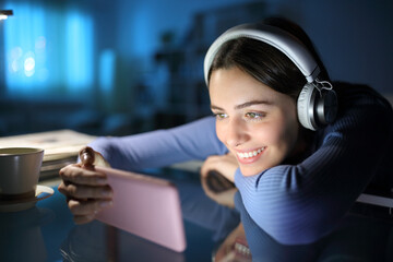 Happy woman watching media with phone and headphones