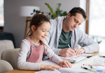 Father helping daugther with homework indoors at home, distance learning.