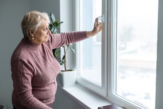 Portrait of senior woman standing at the window at her home