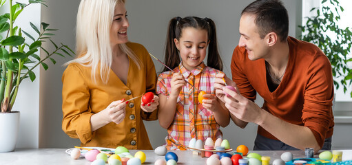 Happy easter! family mother, father and children having fun paint and decorate eggs for holiday