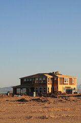 Obraz premium Partially completed two-story home in a desert lot, representing suburban housing construction, real estate development, and residential infrastructure expansion in arid environments