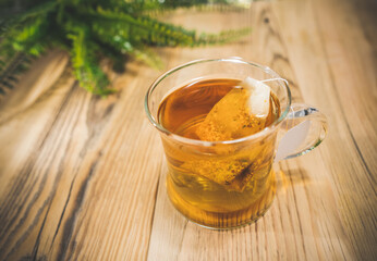 Teacup with bag and herbal leaves on wooden table, selective focus.