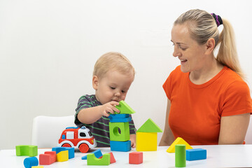 Mom and son play cubes and laugh at the bright background. high quality