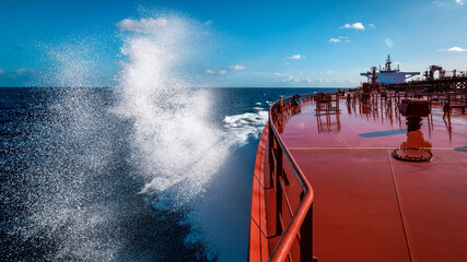 Sea water splashes on bow area of super tanker proceeding by ocean