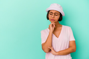 Young mixed race woman isolated on blue background looking sideways with doubtful and skeptical expression.