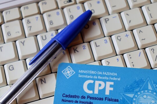 Bahia, Brazil - February 3, 2021: Natural Persons Register (CPF - Cadastro de Pessoas F&iacute;sicas) and pen on top of computer. CPF number is the Brazilian individual taxpayer registry identification.

