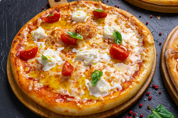 Classic Italian Four Cheese Pizza with Mozzarella, Brie, Dor Blue, Radamir on a dark wooden background with ingredients around (close top view)