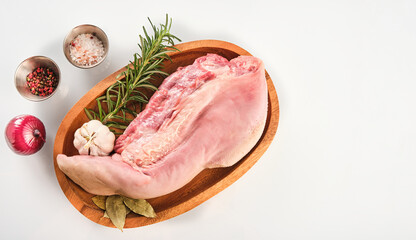 Raw cow tongue with greenery, garlic and dry peppers, close up, top view, high angle, white background.