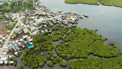 Town in wetlands and mangroves on the ocean coastline from above. Siargao island, Philippines.