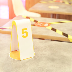 Yellow black tape in cafe. Social distance. Separate people in restaurant. Order number at table....