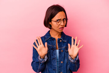 Young mixed race woman isolated on pink background standing with outstretched hand showing stop...