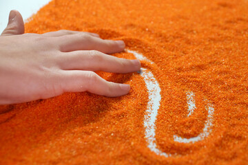 sand therapy, child's hand draws on the orange sand