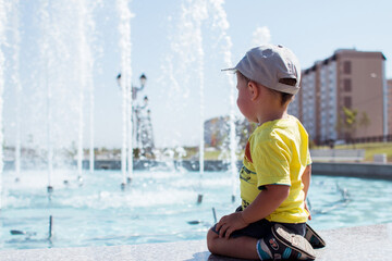 a little boy sits by the fountain