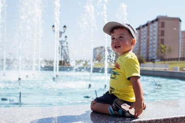 a little boy sits by the fountain