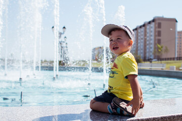a little boy sits by the fountain