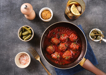 Homemade meatballs with tomato sauce and spices served in  pan on grey background. Top View