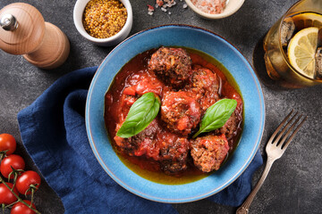 Meatballs in tomato sauce. Homemade swedish meatballs with  tomato sauce in blue plate over grey background. Top view, flat lay, close up.
