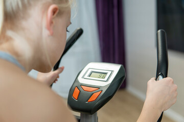 partial focus on hands of girl doing fitness on an exercise bike at home. high quality