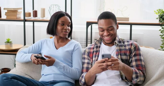 Couple using mobile phones and talking at home