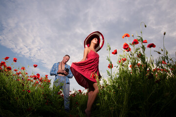 Photographer shooting lady in dress at poppy summer field. Well being lovers family, carefree...