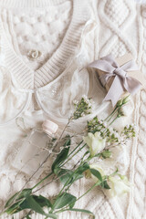 Obraz na płótnie Canvas Stylish lingerie, perfume, modern jewelry and gift on sweater with spring flowers. Soft trendy image