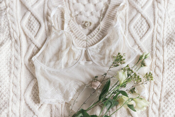 Stylish lingerie, perfume,  jewelry and spring flowers on sweater. Soft trendy image. Fragrance